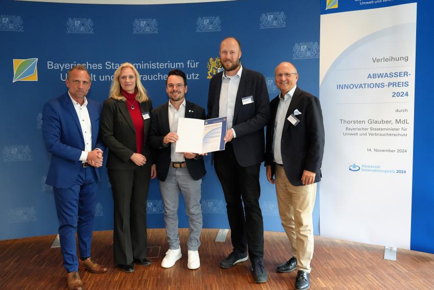 Der dritte Platz des Abwasserinnovationspreis 2024 geht an das AWA Ammersee Wasser- und Abwasserbetriebe gKU für ihr Projekt „Schwimmende Photovoltaikanlage auf Schönungsteich der Kläranlage“. Das Gruppenfoto zeigt Umweltminister Thorsten Glauber (li.), 1. Bürgermeisterin von Dießen am Ammersee Sandra Perzul, Vorstand der Ammerseewerke gKU Maximilian Bleimaier und Thomas Obermeier halten die Auszeichnungsurkunde, 1. Bürgermeister von Herrsching am Ammersee Christian Schiller.