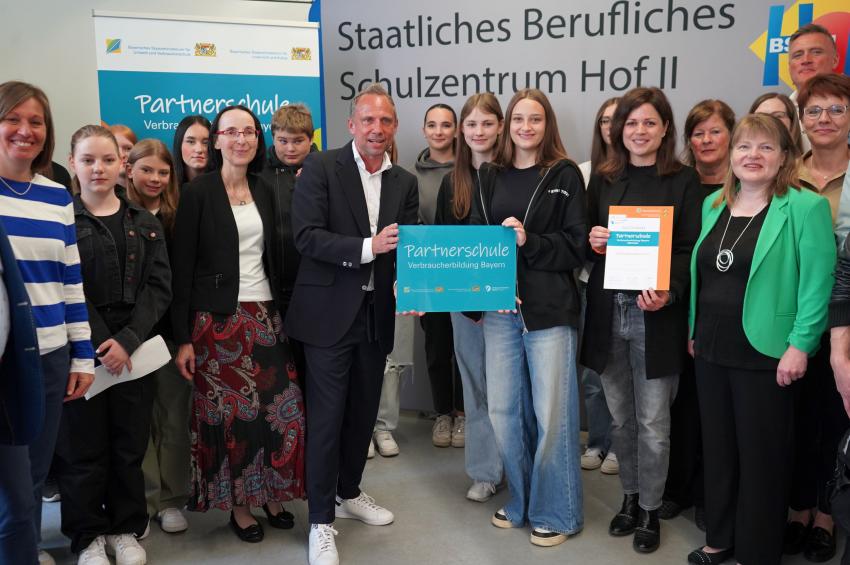 Das Gruppenfoto zeigt Verbraucherschutzminister Thorsten Glauber, Schüller und Lehrkräfte. Die staatl. Wirtschaftsschule Hof wird als Partnerschule Verbraucherbildung Bayern ausgezeichnet.