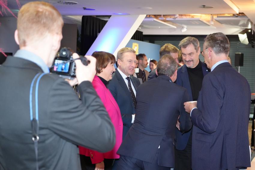 Das Gruppenfoto zeigt den Bayerischen Ministerpräsidenten Markus Söder und Umweltminister Thorsten Glauber, sie begrüßen sich. Links zu sehen sind die Präsidentin des VDA Hildegard Müller und Vorstandsvorsitzender der BMW AG Oliver Zipse, rechts steht der Generalbevollmächtigter der BMW AG Maximilian Schöberl.