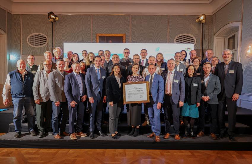 Gruppenfoto mit Landwirtschaftsministerin Michaela Kaniber, Nationalparkleiterin Ursula Schuster hält das IUCN-Zertifikat, Umweltminister Thorsten Glauber und weitere Gäste.