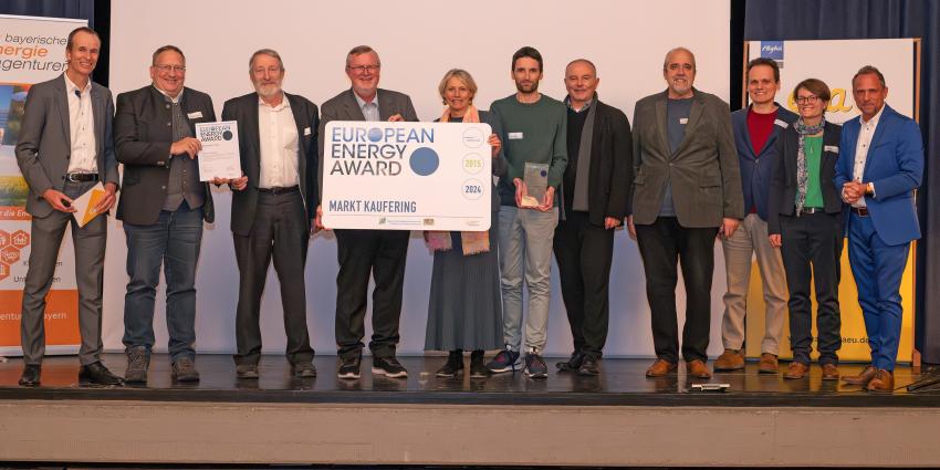 Das Gruppenfoto zeigt Umweltminister Thorsten Glauber (re.), Martin Sambale (Geschäftsführer der eza!, Berater für Immenstadt und Moderator der Veranstaltung, li.) und die Preisträgerinnen und Preisträger der Gemeinde Markt Kaufering (Lkr. Landsberg am Lech). Foto: eza!/Thomas Gretler